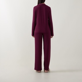 Model wearing DKNY Maroon Banner pyjamas, back view, long-sleeve top and wide-leg trousers in ribbed fabric.