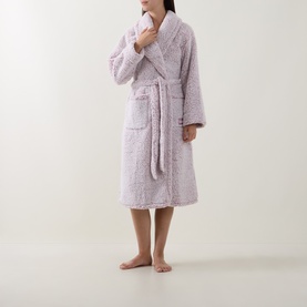 Model wearing DKNY Dusty Mauve Frosted Sherpa Robe, mid-length with shawl collar, tie belt and front pocket, holding a face cloth.
