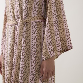 Model wearing DKNY Dusky Green Logo Stripe Robe, belted at waist, with wide sleeves and allover monogram print.