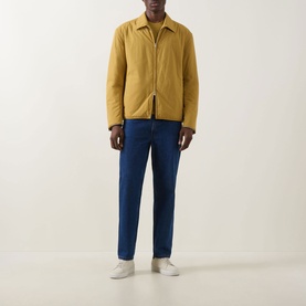 Model wearing Boss Black Casual gold casual jacket with zip fastening, styled with blue jeans and white trainers.