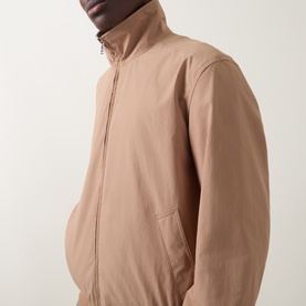 Model wearing Boss Black Casual Medium Beige casual jacket with zip front, funnel neck and side pockets, in 100% polyester fabric.
