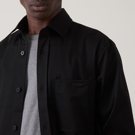 Model wearing Boss Black Casual Owen Solid Logo Shirt in black, styled over a grey crew-neck T-shirt, showing chest patch pocket and tonal logo badge.