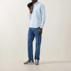 Model wearing Boss Black Casual Open Blue cotton casual shirt with blue jeans and grey trainers, holding dark accessory