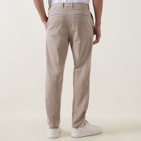 Model wearing Boss Black Casual Open Beige casual trousers, rear view, styled with white trainers.