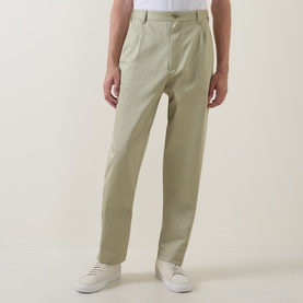 Model wearing Boss Black Casual Kai Pleated Trousers in dark beige, straight-leg with twin front pleats, styled with white trainers and a white tee