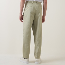 Model wearing Boss Black Casual Kai Pleated Trousers in dark beige, rear view showing buttoned welt pockets and straight-leg silhouette, styled with