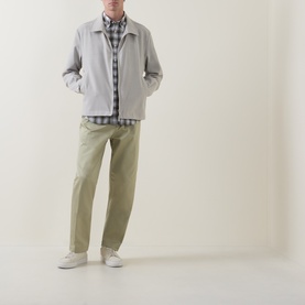 Model wearing Boss Black Casual Kai Pleated Trousers in dark beige, styled with a light grey jacket, check shirt and white trainers.