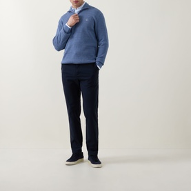 Model wearing Boss Black Casual dark blue casual trousers in cotton-elastane, styled with a blue knit jumper, white shirt and navy suede loafers.