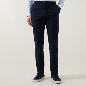 Model wearing Boss Black Casual dark blue cotton casual trousers, styled with a light blue shirt and white trainers.