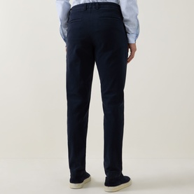 Model wearing Boss Black Casual dark blue casual trousers, rear view, styled with a light blue shirt and beige suede shoes.