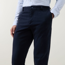 Model wearing Boss Black Casual dark blue cotton casual trousers with tapered leg, styled with a light blue striped shirt.