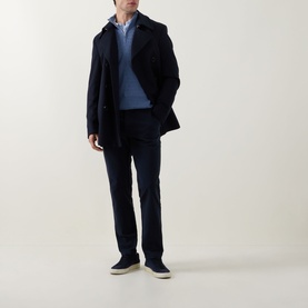 Model wearing Boss Black Casual dark blue casual trousers in cotton-elastane, styled with a navy coat, blue jumper and light-coloured loafers.