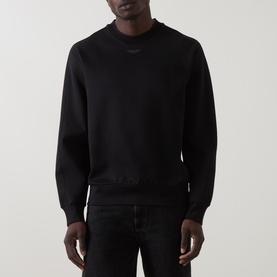 Model wearing Boss Black Casual black cotton-blend crew neck sweatshirt with tonal chest logo, styled with black jeans.