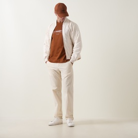 Model wearing Boss Black Casual Medium Brown crew neck T-shirt, styled with cream bomber jacket, cream trousers and white trainers.
