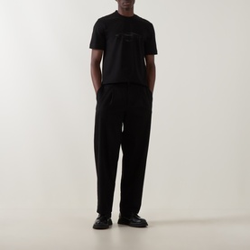 Model wearing Boss Black Casual Taut Logo T-Shirt in black with car graphic, paired with black wide-leg trousers and black loafers.