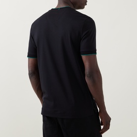 Model wearing Boss Black Casual Thompson Logo T-Shirt in black, rear view, showing green contrast tipping at crew neck and cuffs, straight hem with