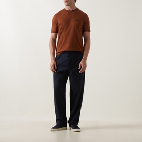 Model wearing Boss Black Casual medium brown cotton crew neck T-shirt with navy trousers and cream slip-on shoes.