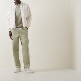 Model wearing Boss Black Casual C-Sharpe Logo Sweatshirt in Dark Beige, styled with a light pink padded jacket and sage green chinos.