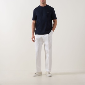 Model wearing Boss Black Casual C-Taut 01 Logo T-Shirt in dark blue with white trousers and cream trainers.