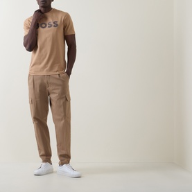 Model wearing Boss Black Casual C-Thompson Logo T-Shirt in medium beige with tan cargo trousers and white trainers.