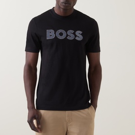 Model wearing Boss Black Casual C-Thompson Logo T-Shirt in black, featuring bold BOSS chest graphic. Styled with beige chinos.