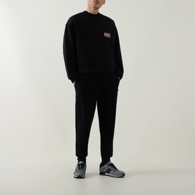 Model wearing Boss Black Casual C-Tigerman Logo Sweatshirt in black with matching black trousers and grey trainers.