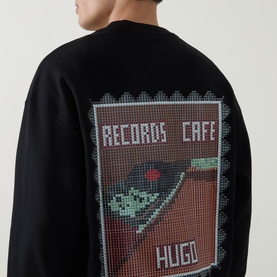 Model wearing Boss Black Casual C-Tigerman Logo Sweatshirt in black, showing rear Records Caf&eacute; pixel-style graphic print on crew neck sweat.