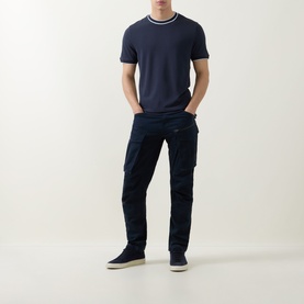 Model wearing Boss Black Casual Thompson Tipped T-Shirt in dark blue with tipped crew neck, styled with navy cargo trousers and navy trainers.