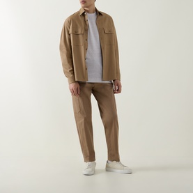 Model wearing Boss Black Casual Thompson Textured Logo T-Shirt in Open White, styled with tan overshirt, taupe trousers and white trainers.