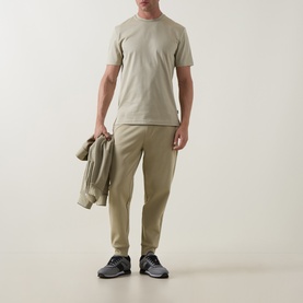 Model wearing Boss Black Casual Thompson Logo T-Shirt in Dark Beige, styled with matching tapered trousers and dark trainers, carrying a jacket.