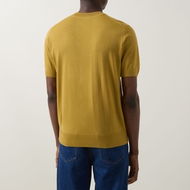Model wearing Boss Black Casual gold virgin wool crew neck knit T-shirt, rear view, styled with blue jeans.