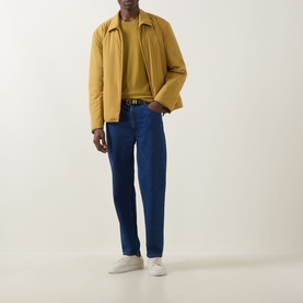 Model wearing Boss Black Casual gold virgin wool crew neck, styled with yellow zip jacket, blue jeans and white trainers.