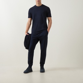 Model wearing Boss Black Casual Thompson Logo T-Shirt in dark blue, styled with matching navy joggers and dark trainers.
