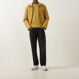 Model wearing Boss Black Casual gold crew neck T-shirt in 100% cotton, styled with yellow jacket, dark jeans and white trainers.