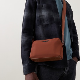 Model carrying Boss Black Casual medium brown crossbody bag with dark hardware, adjustable shoulder strap, styled with plaid jacket