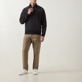 Model wearing Boss Black Casual black cotton half-zip sweatshirt, styled with tan trousers and white trainers.
