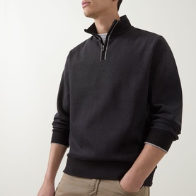 Model wearing Boss Black Casual black cotton half-zip sweatshirt with contrast zip detail, styled with beige trousers