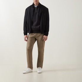 Model wearing Boss Black Casual black cotton half-zip sweatshirt, styled with black bomber jacket, tan chinos and white trainers.