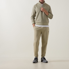 Model wearing Boss Black Casual Sidney Half-Zip Sweatshirt in dark beige with matching joggers, white T-shirt, and dark trainers.