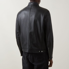 Model wearing Boss Black Casual black lamb leather jacket, rear view, with silver snap-button cuffs, styled with dark denim jeans.