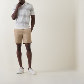 Model wearing Boss Black Casual C-Lamoroso Striped Knitted Polo in Open White, styled with tan shorts and white trainers.
