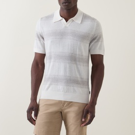 Model wearing Boss Black Casual C-Lamoroso Striped Knitted Polo in Open White, with open placket and short sleeves, styled with beige chinos