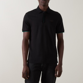 Model wearing Boss Black Casual black cotton polo shirt with contrast green tipped cuffs and tonal logo detail, paired with black trousers.
