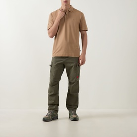 Model wearing beige polo shirt styled with olive cargo trousers and brown hiking boots