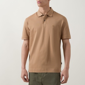 Model wearing camel cotton polo shirt with three-button placket and small chest logo, styled with khaki trousers