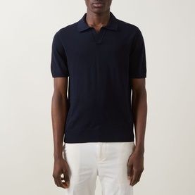 Model wearing Boss Black Casual dark blue virgin wool knit polo shirt with open collar, styled with white trousers.