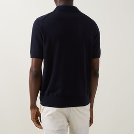 Model wearing Boss Black Casual dark blue virgin wool knit polo shirt, back view, paired with white trousers