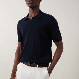 Model wearing Boss Black Casual dark blue virgin wool knit polo shirt, styled with white trousers and brown leather belt