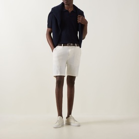 Model wearing Boss Black Casual Dark Blue virgin wool polo, styled with white shorts, brown belt and white trainers.