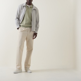 Model wearing Boss Black Casual H Lomarino Logo Polo Sweater in dark beige, styled with a grey jacket, cream trousers and white trainers